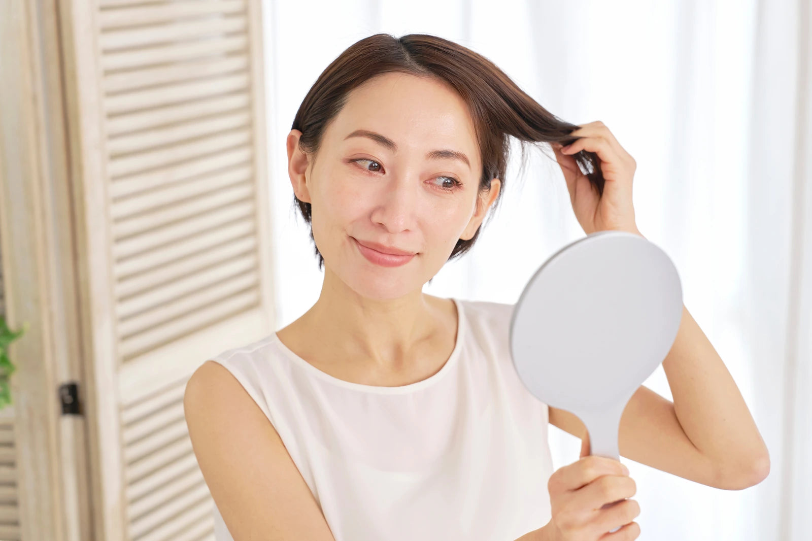 鏡を見ながら髪を整える女性
